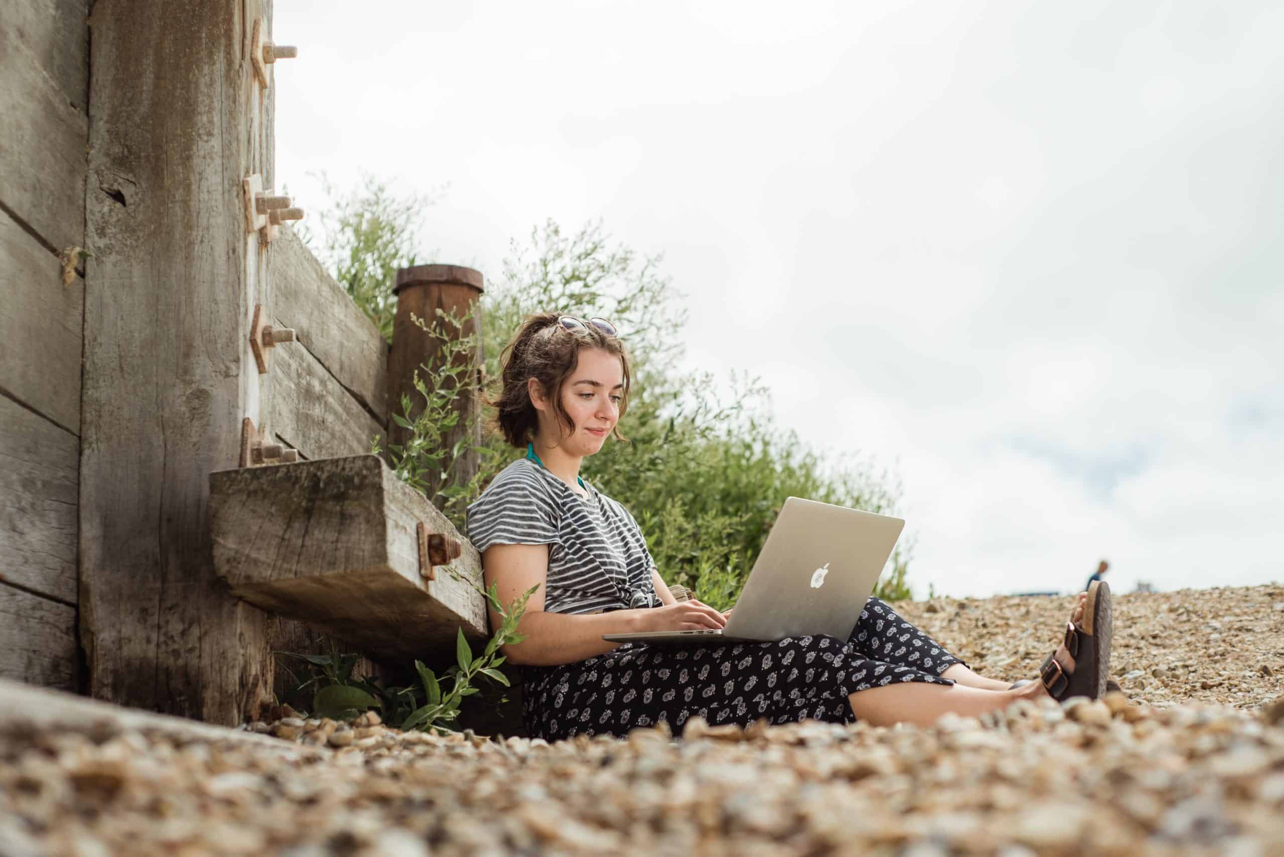 NEC female student with laptop on beach