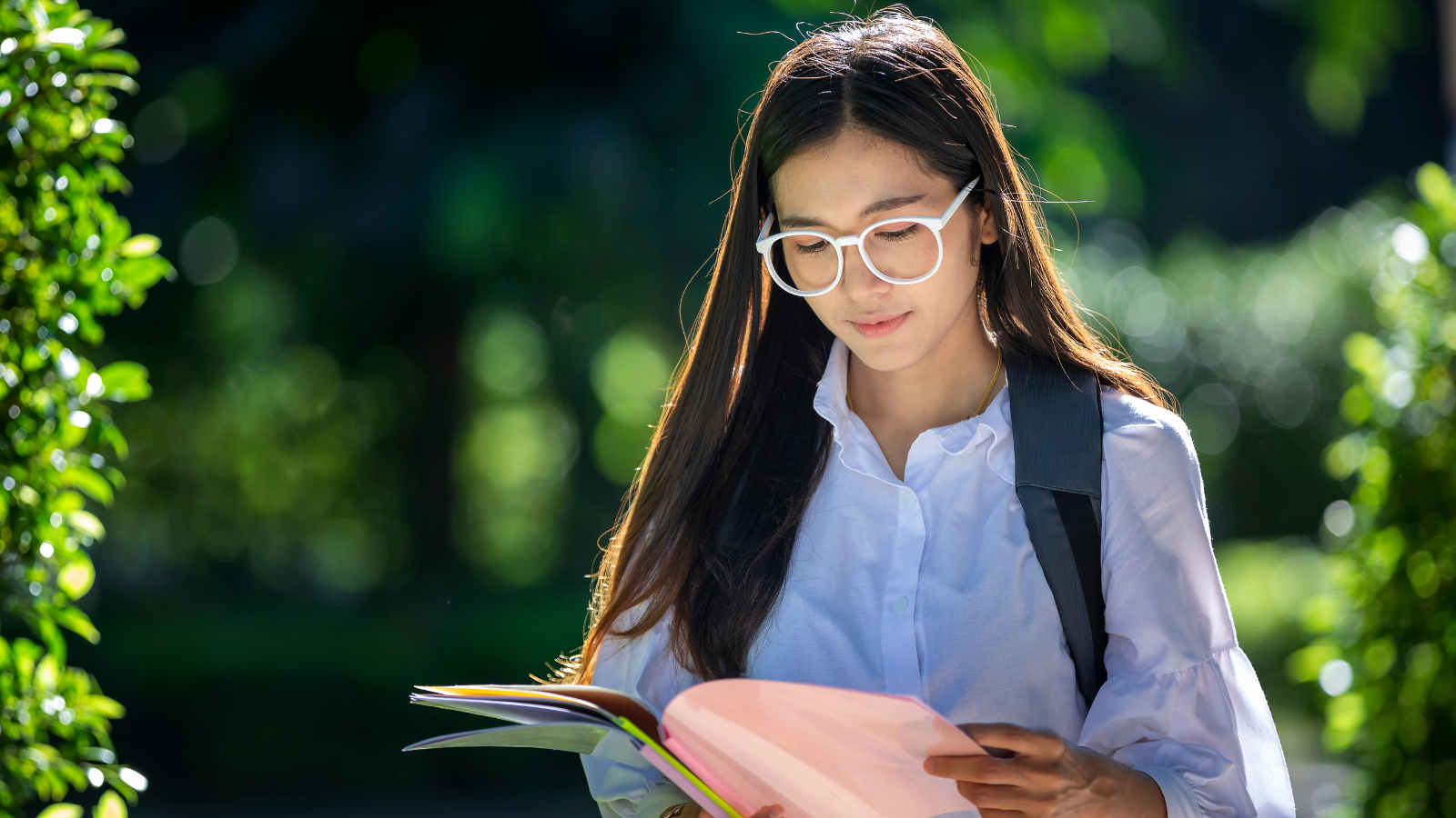 Teenage girl in glasses looking through her study notes.