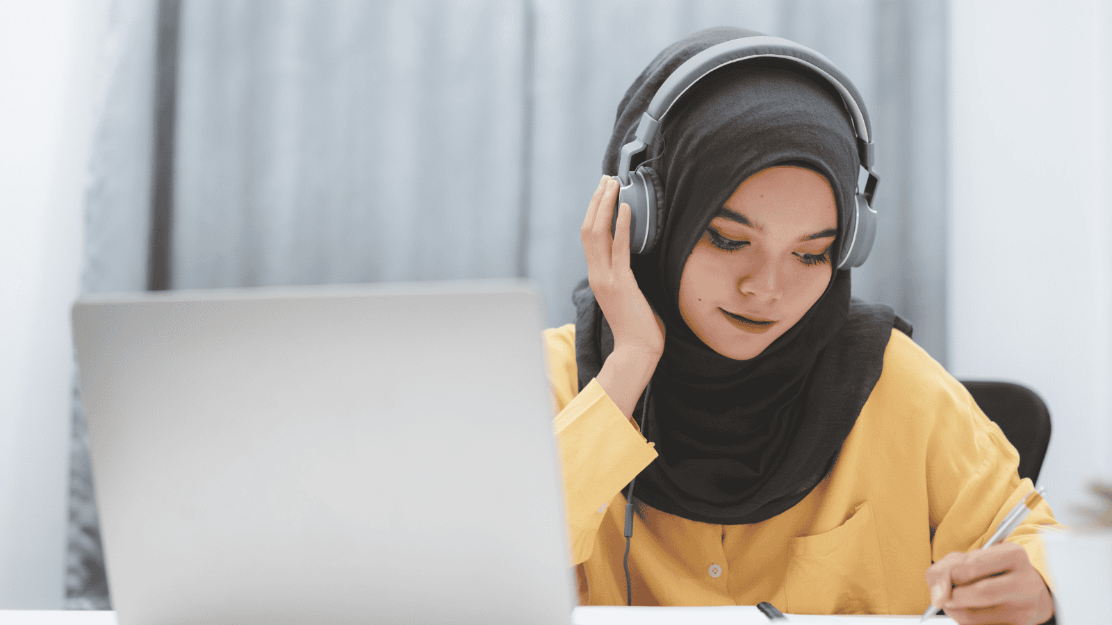 Asian girl in head covering studying at her laptop