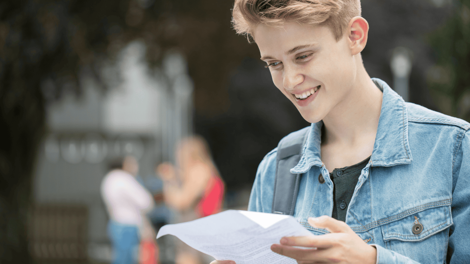 Teenage boy looking at a sheet or paper with a slight smile on his face.