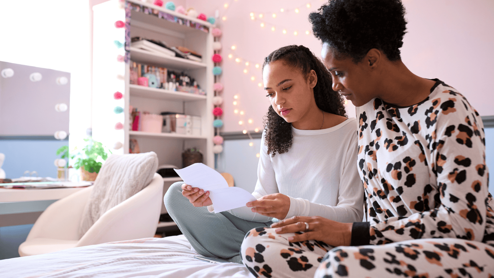 Disappointed teenage girl looking at her exam results, supported by her mother.