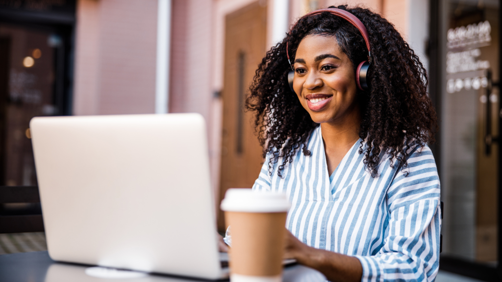 Woman sitting at computer in a cafe, smiling.