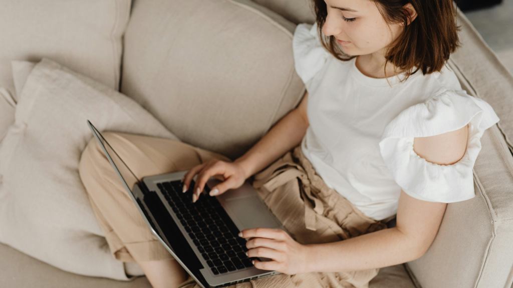 female sitting on sofa on laptop, looking at NEC's learning design